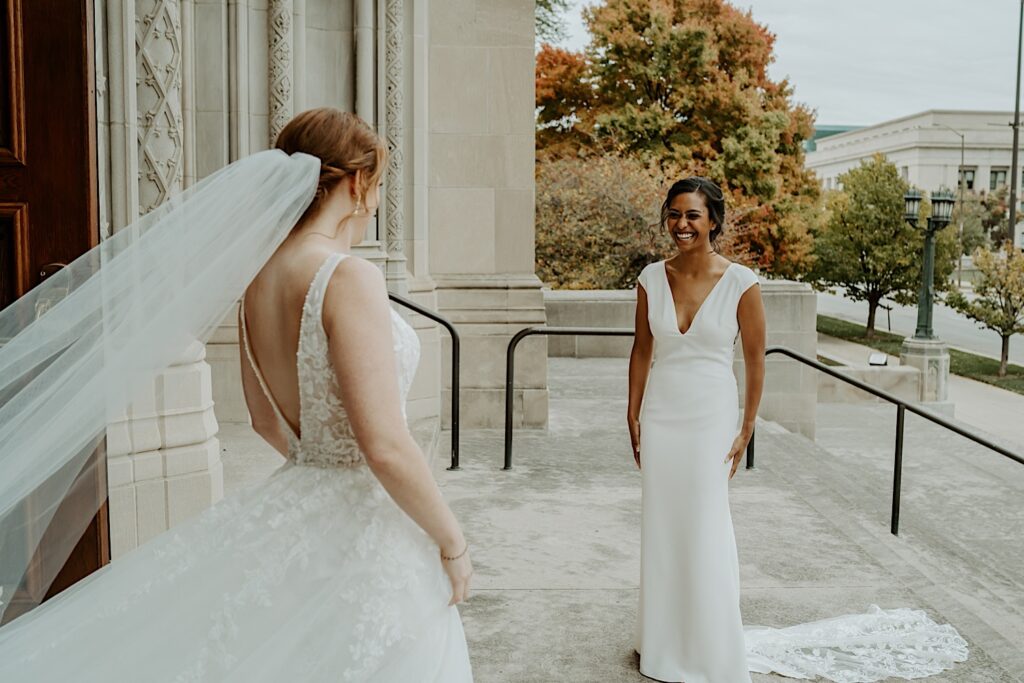 Brides look at each other and smile for their first look before their wedding ceremony at Scottish Rite Cathedral. 