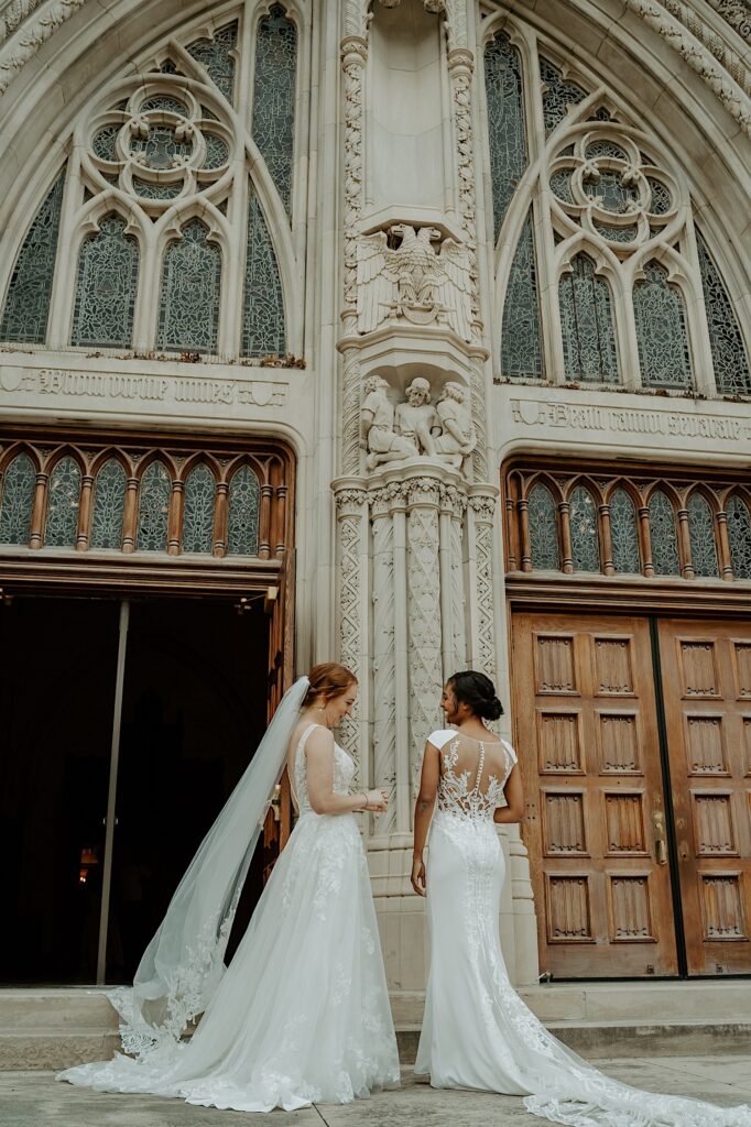 Brides stand and talk with each other in front of Scottish Rite Cathedral before their wedding ceremony.