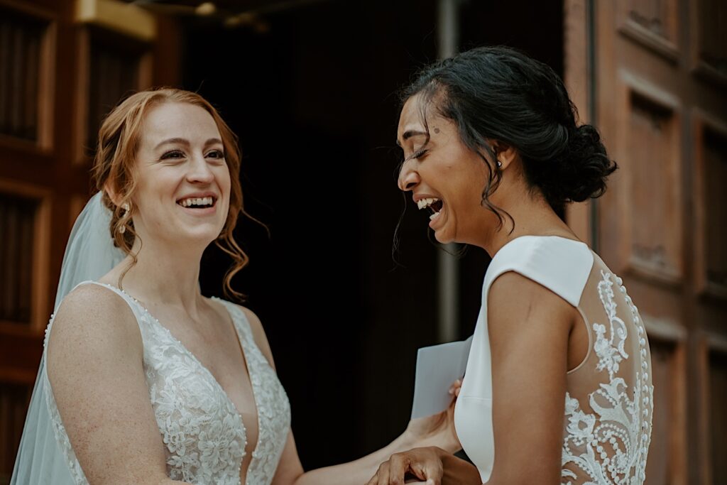 Brides giggle while they share notes to each other before their LGBTQ+ ceremony at Scottish Rite Cathedral in Indianapolis. 