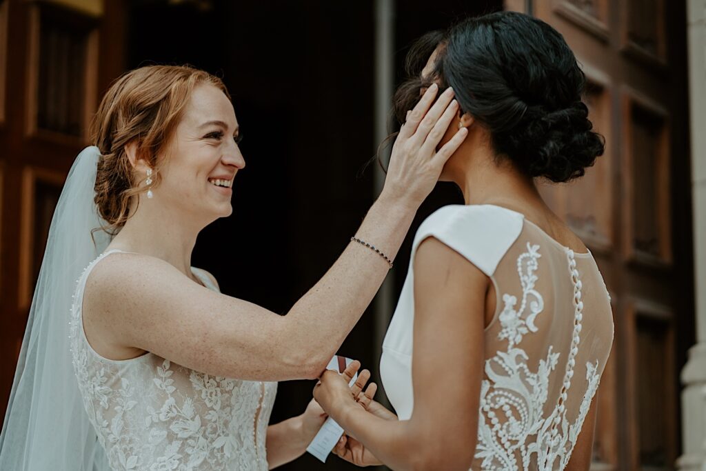 Brides places her hand on her soon to be wife's face as they exchange letters before their wedding ceremony at Scottish Rite Cathedral in Indianapolis. 