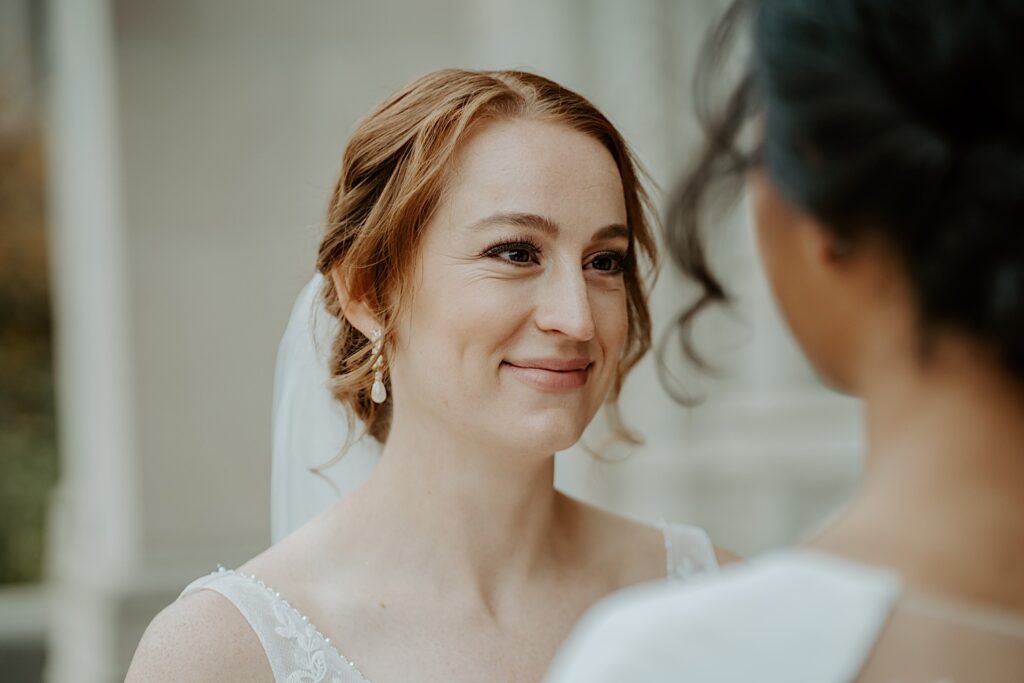 Bride smiles beautifully as she looks in to her fianceé's eyes before their LGBTQ+ ceremony in Indianapolis. 