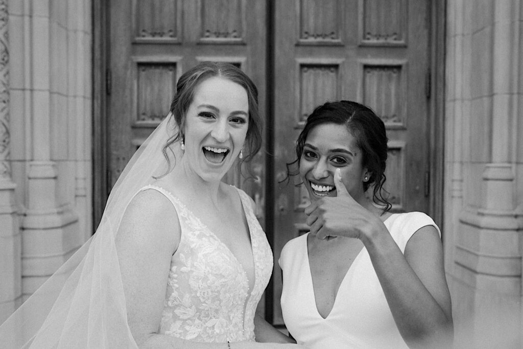 Bride holds a thumbs up as she leans towards her fianceé for a candid wedding portrait outside Scottish Rite Cathedral in Indianapolis. 