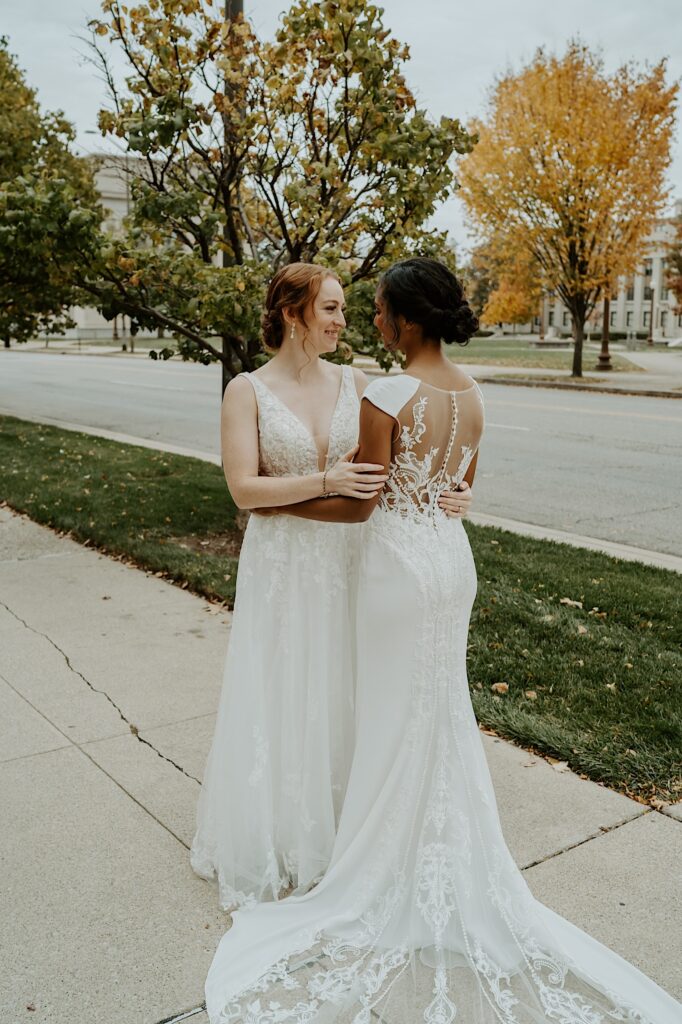 Bride's hug on a sidewalk in downtown Indianapolis with autumn trees lining the street behind them. 