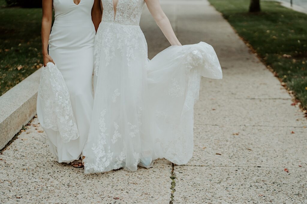 Indianapolis Wedding photographer captures the bottom half of bride's wedding dresses as they stand on the sidewalk. 