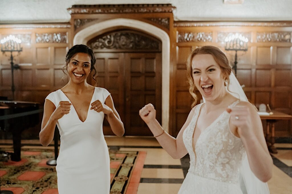 Brides hold up their fists in celebration after their LGBTQ+ wedding ceremony at the Scottish Rite Cathedral. 