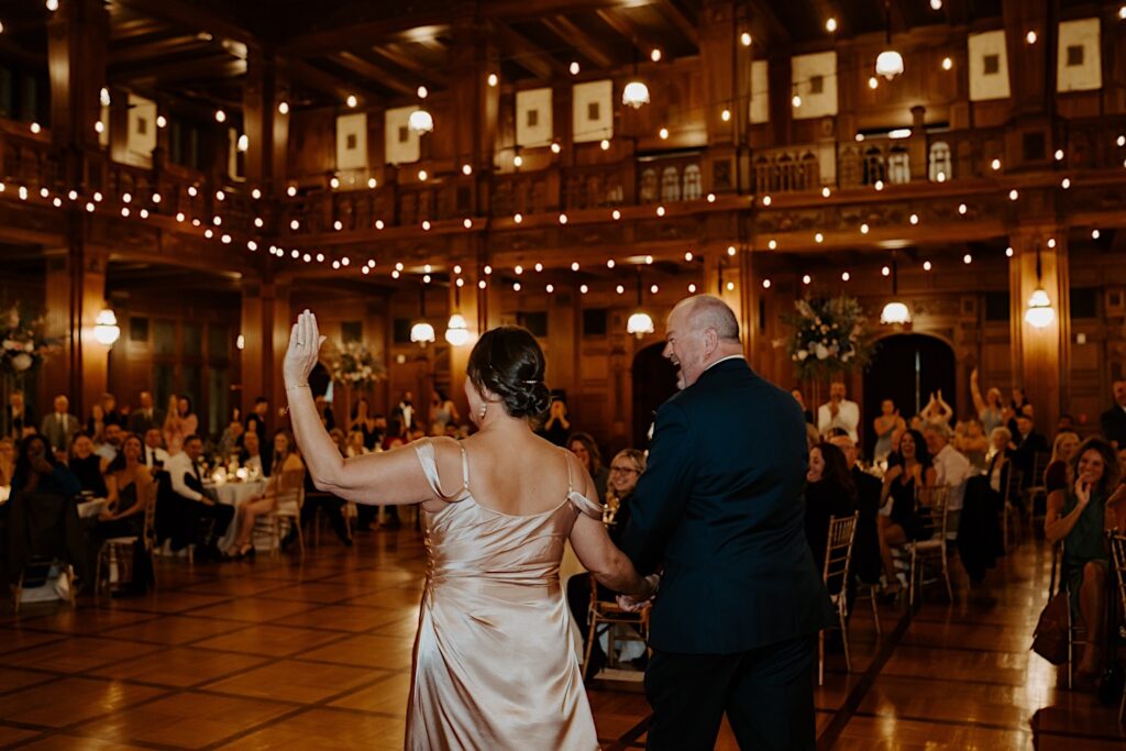 Bride's parents enter the reception room and wave at the guests.