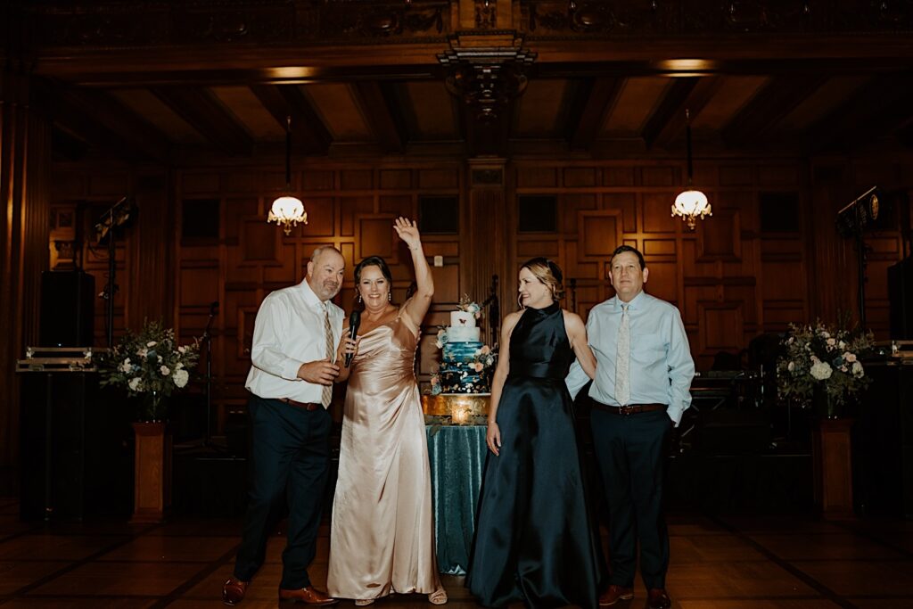 Parents of the brides stand at the head table and smile as they welcome the guests to the wedding reception in Indianapolis. 