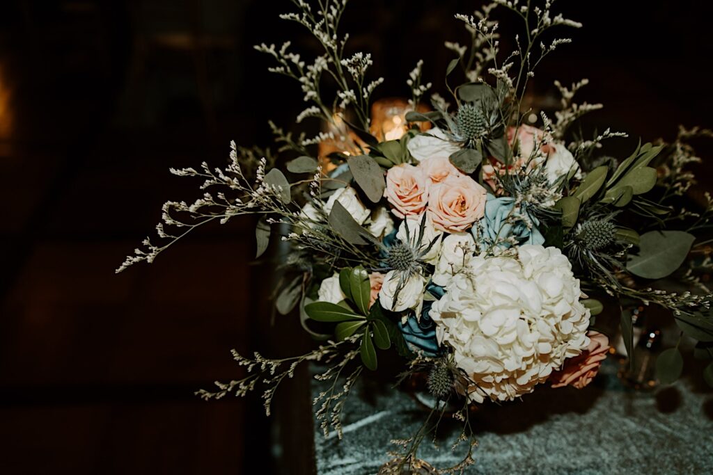 Indianapolis Wedding Photographer captures gorgeous wedding bouquet with blue and pink roses, hydrangeas and green filler sitting on a teal table.