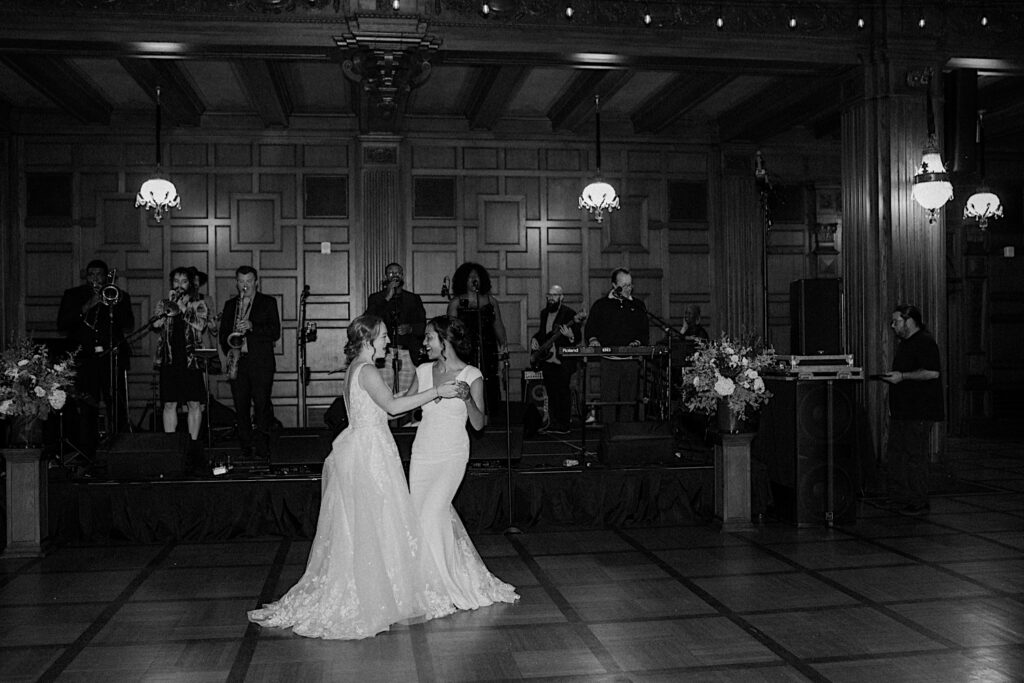 Brides do their first dance with a live band playing behind them in the 1920's style wedding reception hall in Indianapolis.