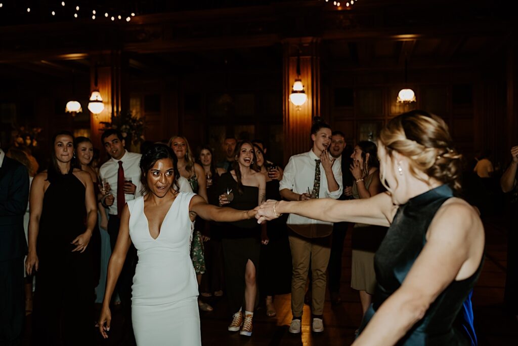 Bride dances with woman in the middle of the dance floor during wedding reception in Indianapolis. 