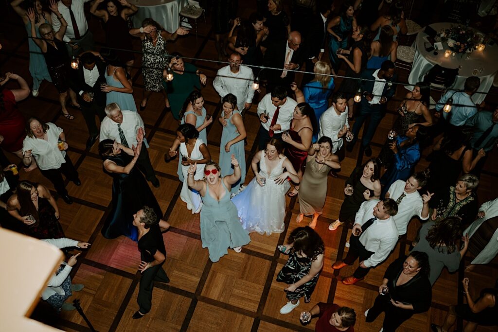 Indianapolis wedding photographer captures guests from balcony above as they dance during their reception. 