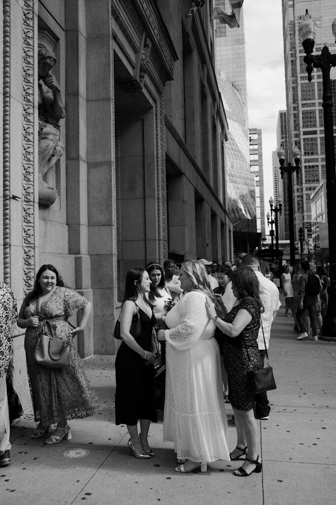 Families gather around bride in a relaxed white dress before elopement ceremony at Chicago City Hall. 