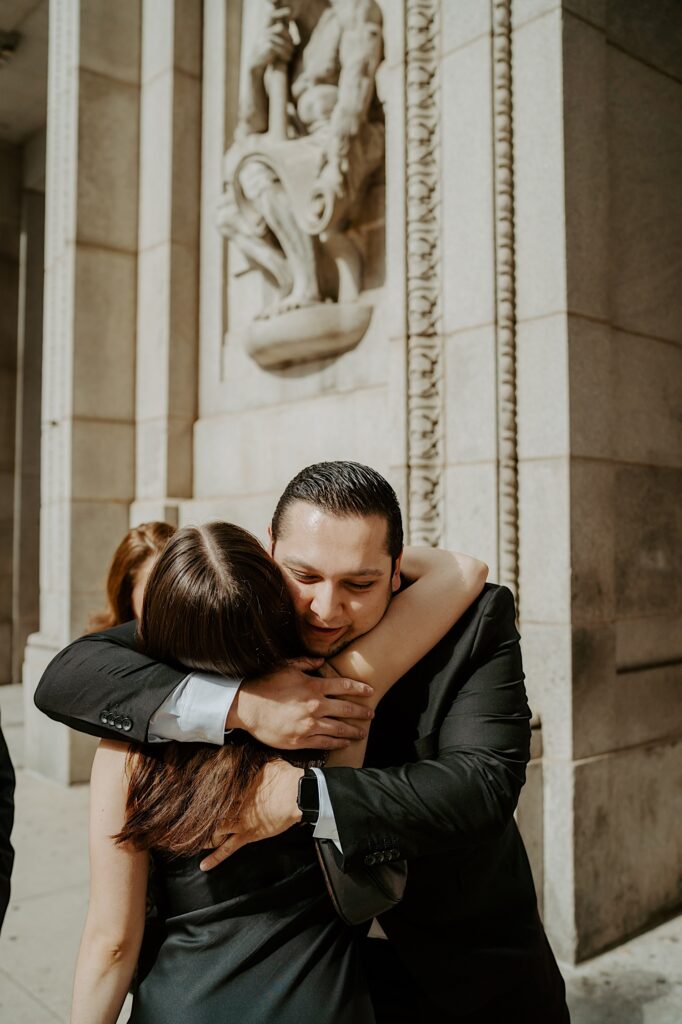 Groom hugs his family before elopement ceremony at Chicago City Hall. 