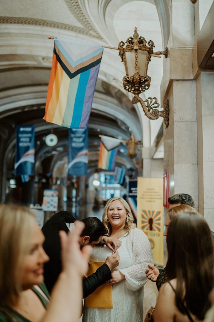 Bride holds a manila envelope as her family stands around her in the hallway of Chicago City Hall before elopement ceremony. 