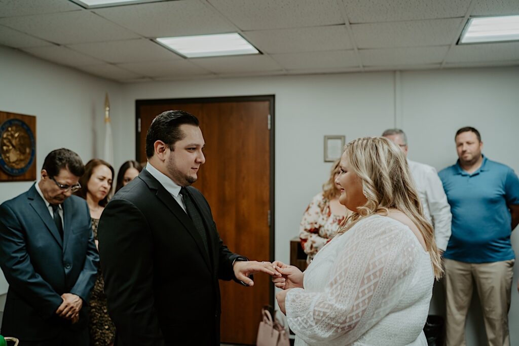 Bride puts ring on Groom's finger during intimate elopement ceremony at City Hall. 