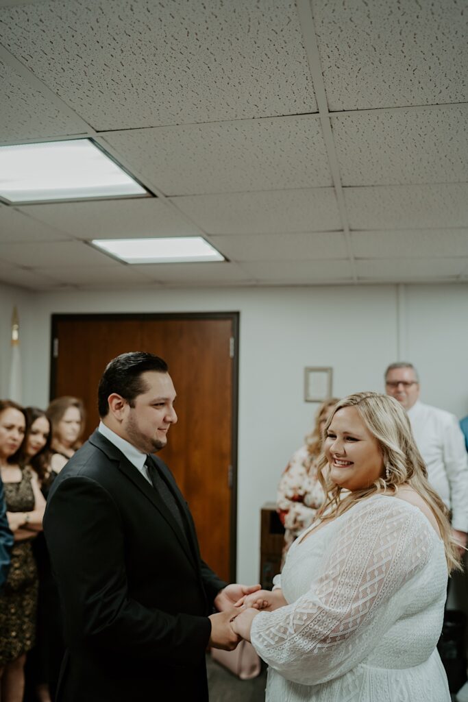 Bride and Groom hold hands during intimate elopement ceremony in Chicago City Hall Room.