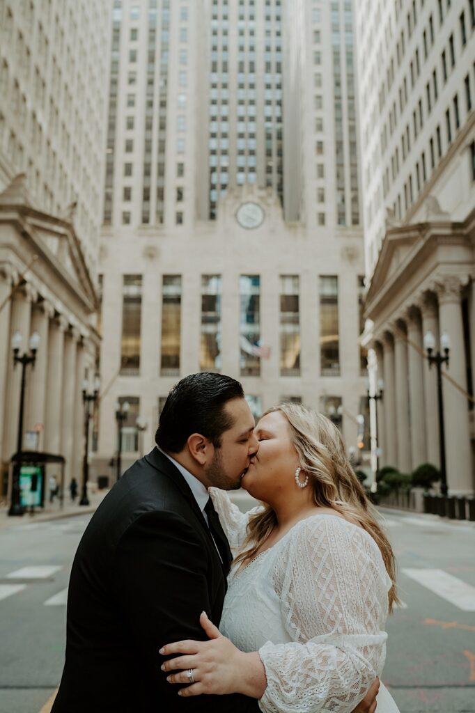 Bride and Groom kiss in the center of the street with the Chicago Board of Trade in the background. 