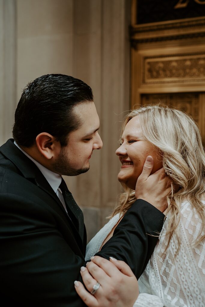 Groom holds Bride's face as she candidly laughs during elopement portraits in Chicago.