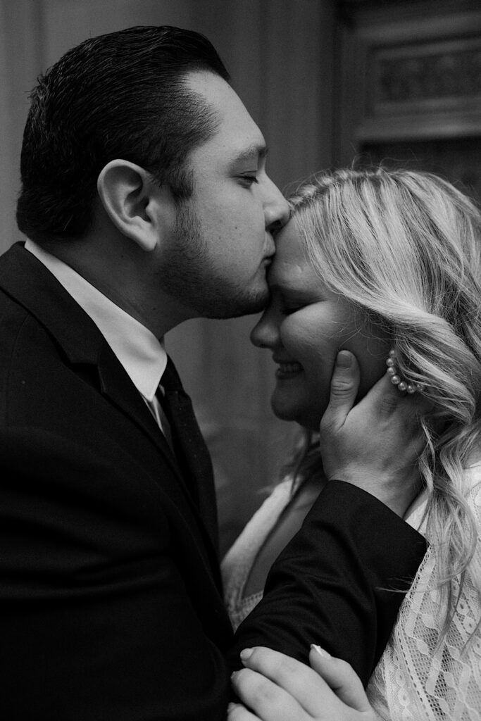 Groom kisses bride's forehead romantically during elopement portraits in downtown Chicago. 