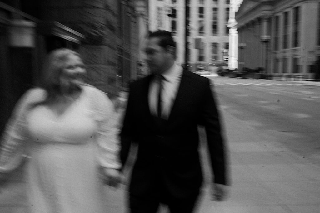 Midwest Wedding photographer captures a fuzzy cinematic style black and white portrait of a couple walking down a street for elopement portraits in downtown Chicago. 