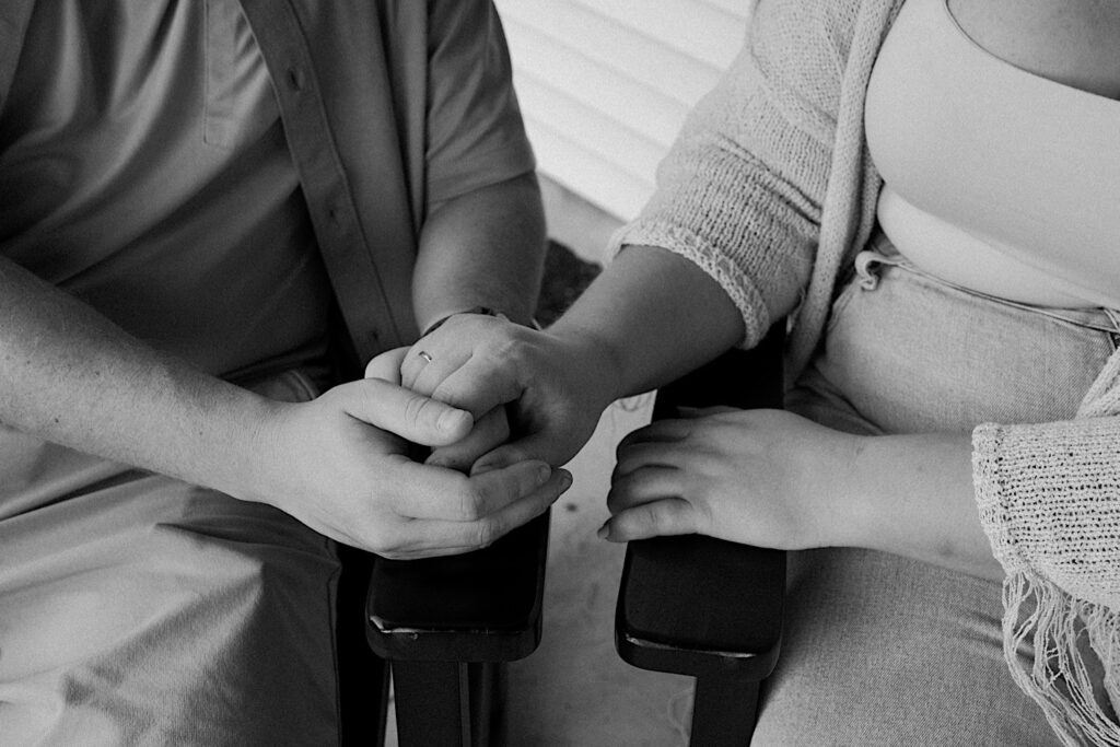 Indiana photographer captures couple holding hands as they sit on rocking chairs on their front porch. 