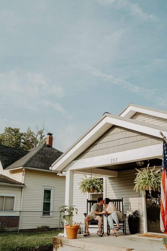 Couple kisses as they sit on rocking chairs on their front porch in their suburban neighborhood in Lafayette Indiana. 