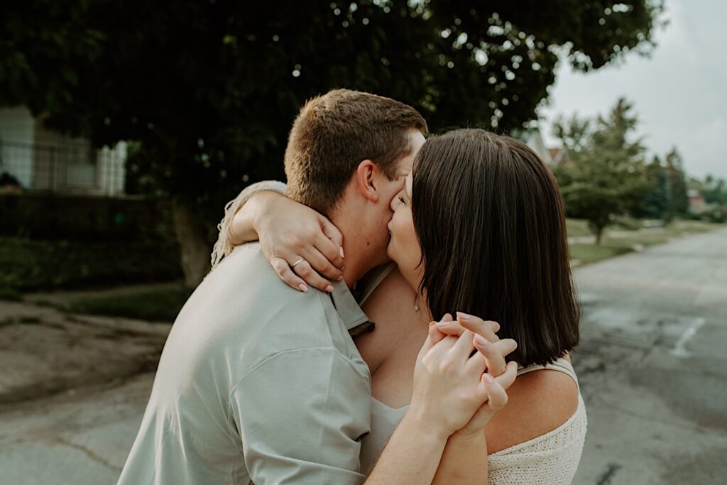 Woman kisses her husband as they walk down their street during intimate portraits in Indiana. 