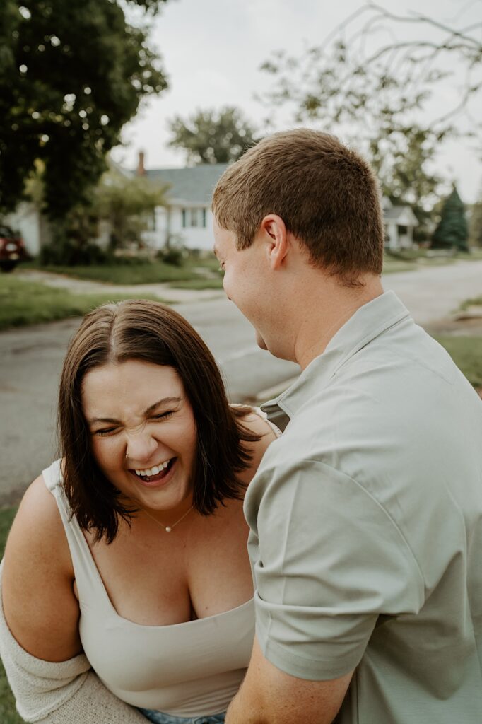 Woman laughs candidly as her husband hugs her during cozy portraits during date night. 