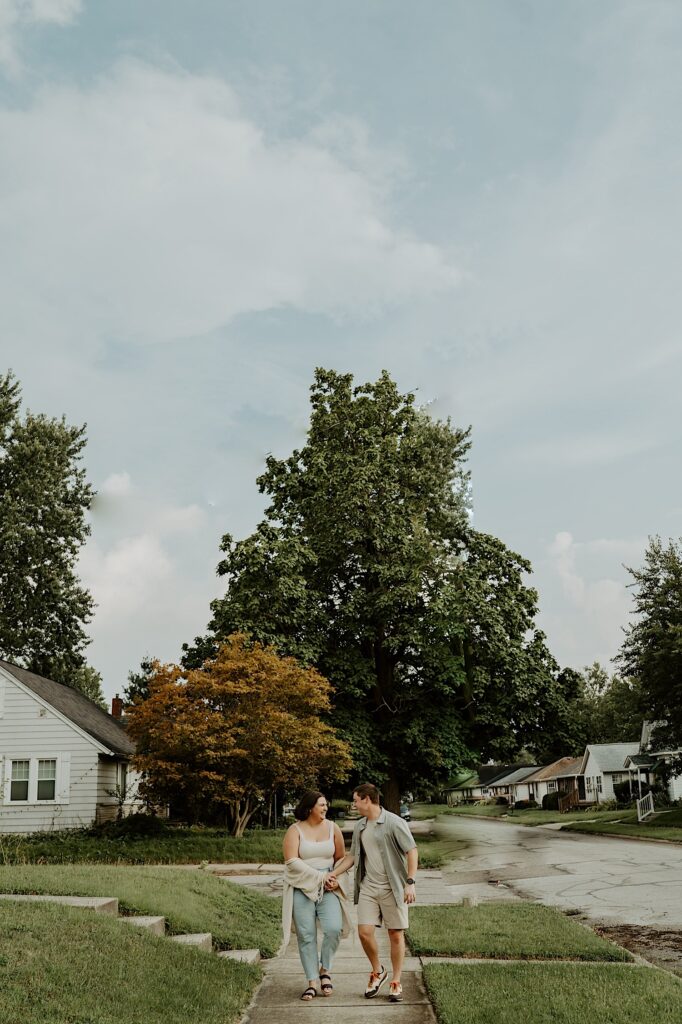 Couple walks towards Indiana wedding photographer and look at each other candidly during couple portraits during date night. 