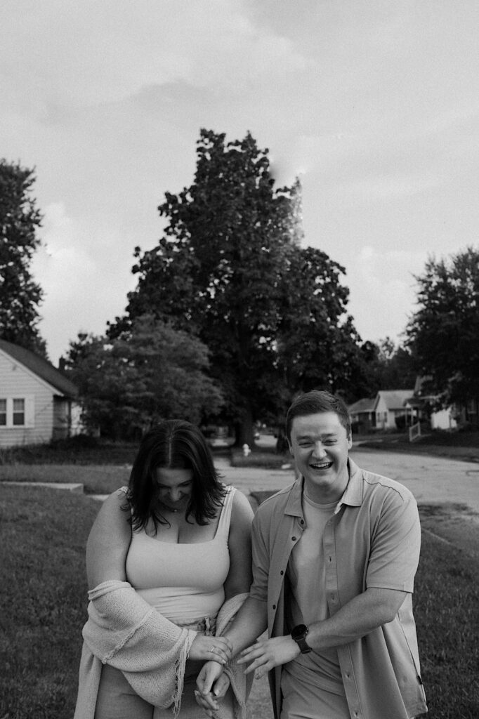 Couple walks towards Indiana photographer and laugh at each other candidly during couple portraits during date night. 