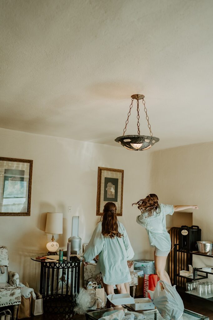 Bridesmaids dance in the getting ready suite of Mt Woodson Castle in Ramona California.  They're wearing oversized button up shirts.  