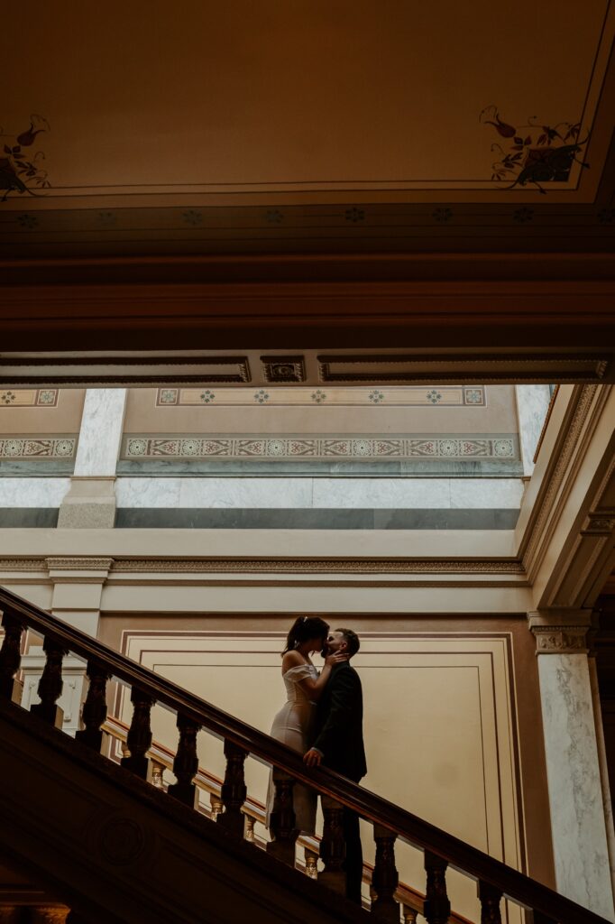 A bride and groom kiss in the shadows of the Indiana State house during their fall elopement.  