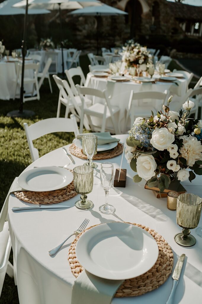 A summer wedding in California with wicker chargers and white roses and green goblets.