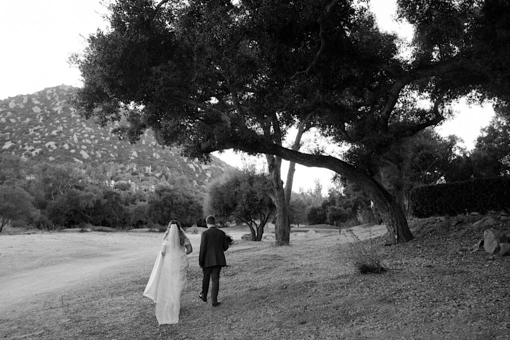 A bride and groom walk together in the California desert at Mt Woodson Castle