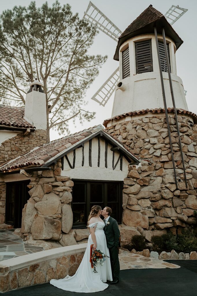 A bride and groom kiss and hold one another overlooking the golf course at Mt Woodson Castle in California. 