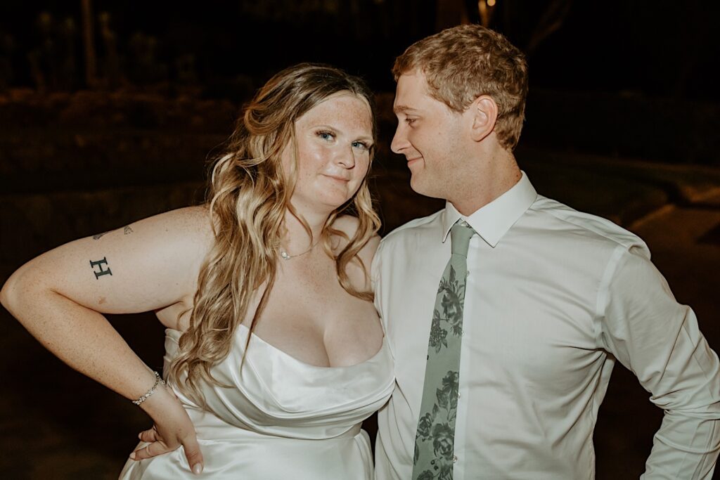 A bride and groom pose for the camera taking a late night photo of them smiling together. 