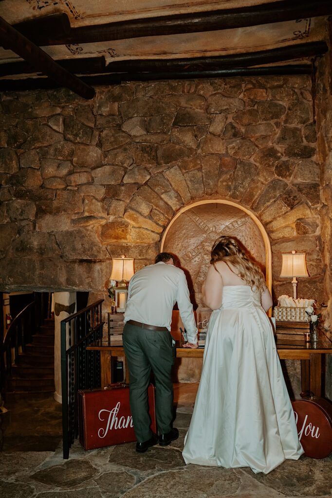 A bride and groom look through their guest book from their wedding day at their wedding reception in California.  