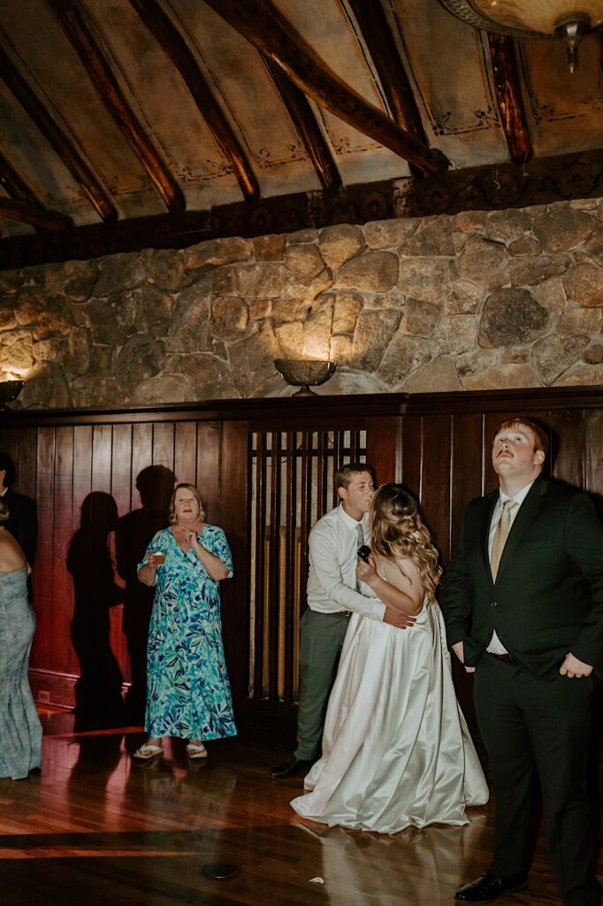 A bride and groom dance together on their wedding day surrounded by guests.