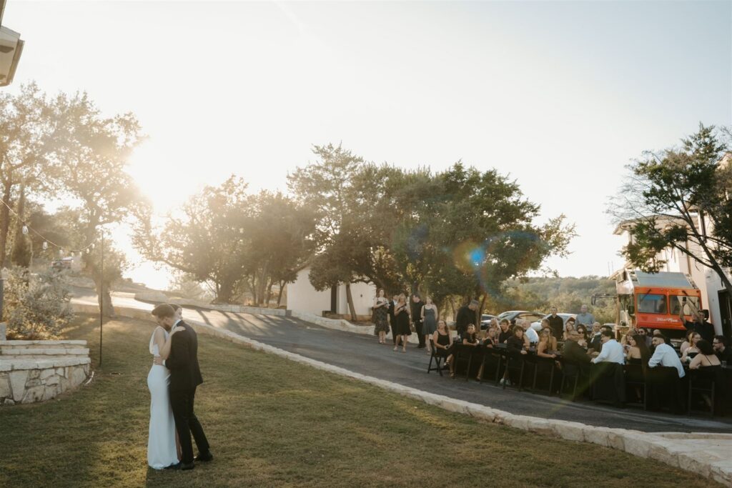 bride and groom dancing together on the lawn of their venue while being watched by their family and friends at an intimate wedding
