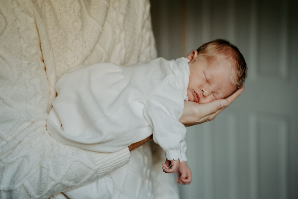 sleeping baby being held by dad in his arms wearing white