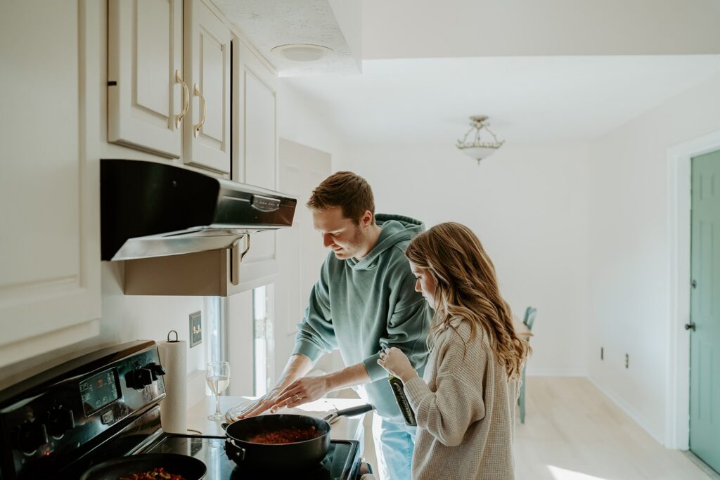 couple in their kitchen cooking pasta sauce together