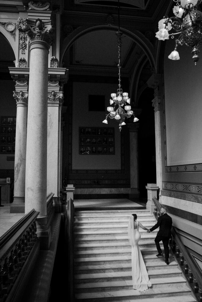 bride and groom walking up a grand staircase at the indiana statehouse