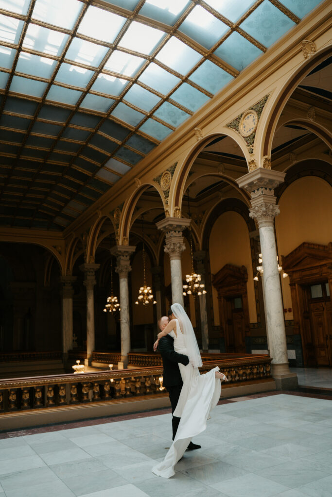 groom spinning bride in the air at a venue inspired by european architecture 
