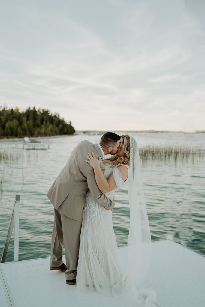 couple kissing in wedding attire on lake