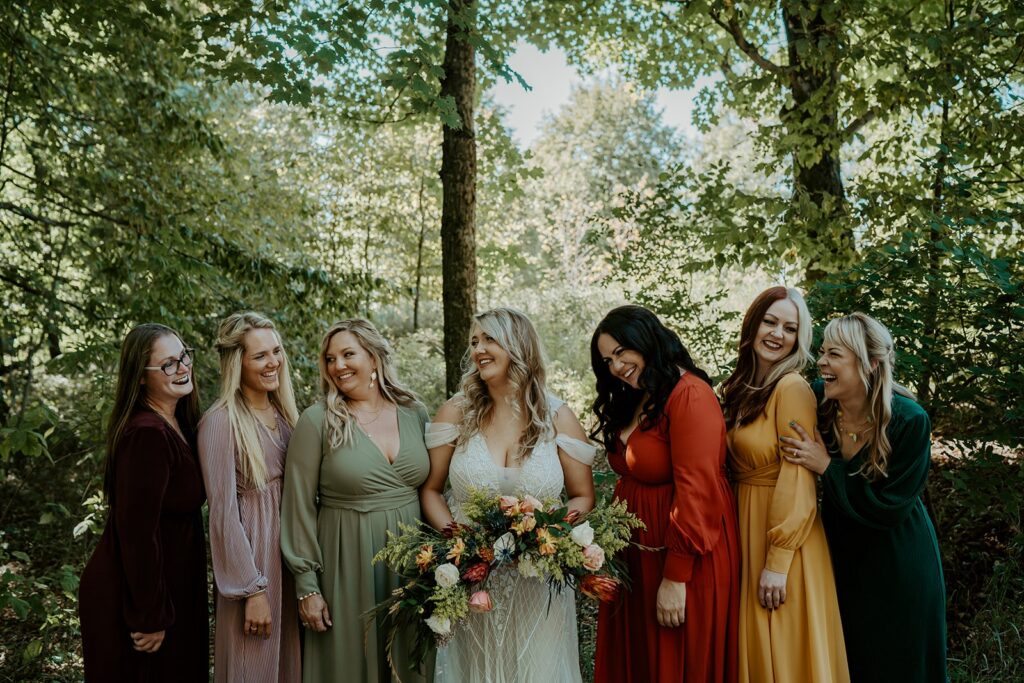 bride and bridesmaids laughing in the woods