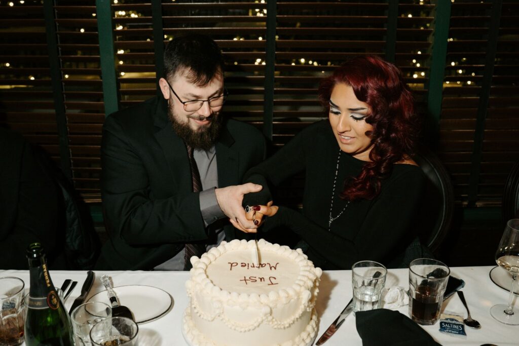 couple cutting into cake that reads "just married"