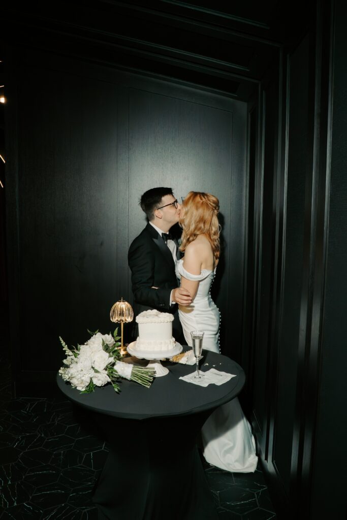 couple kissing in front of cake in dark room