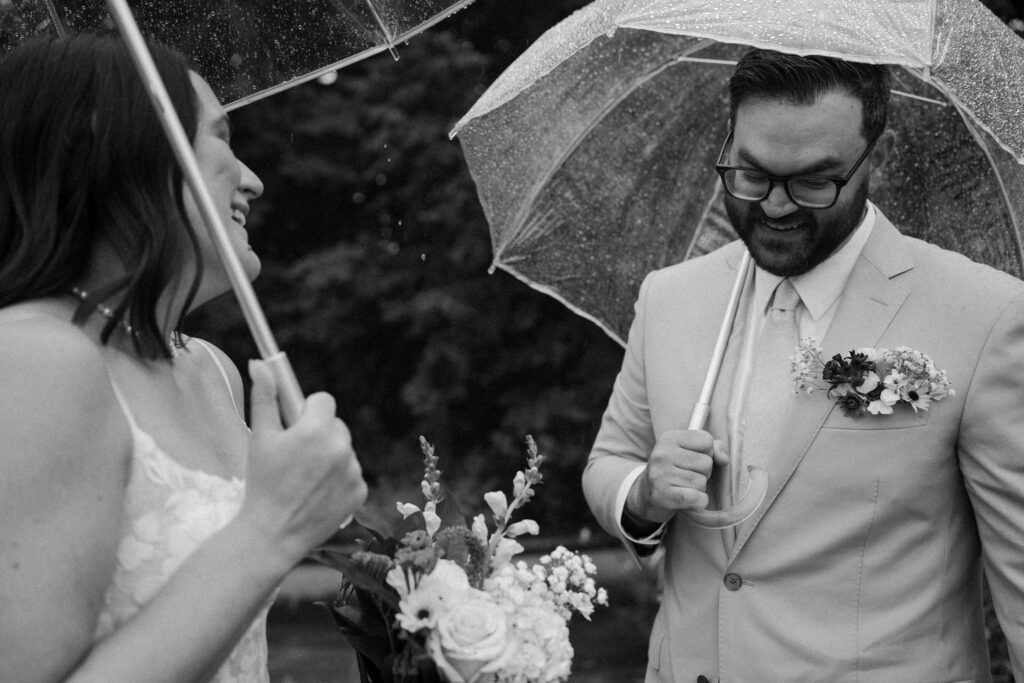 couple laughing under umbrellas during their first look