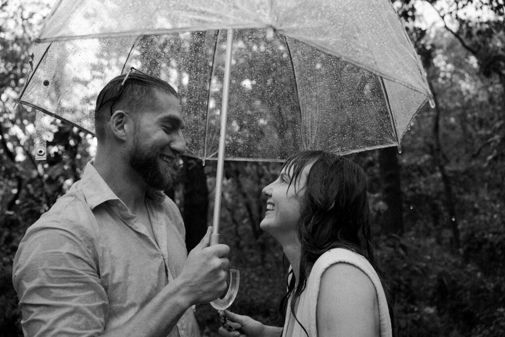 couple laughing under umbrella during rain storm