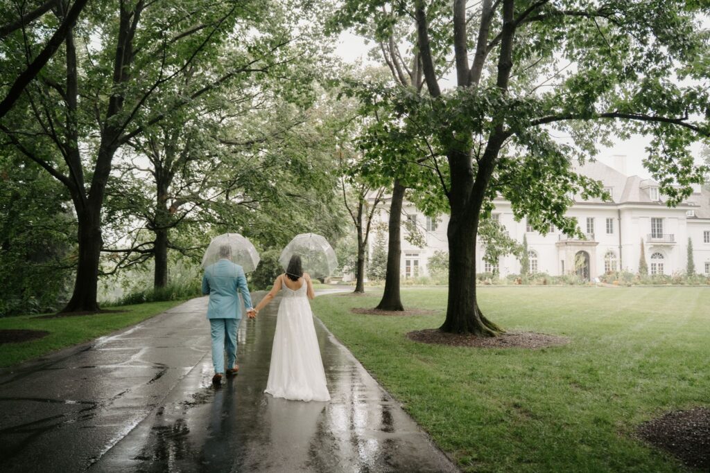 couple walking towards mansion at newfields in the rain